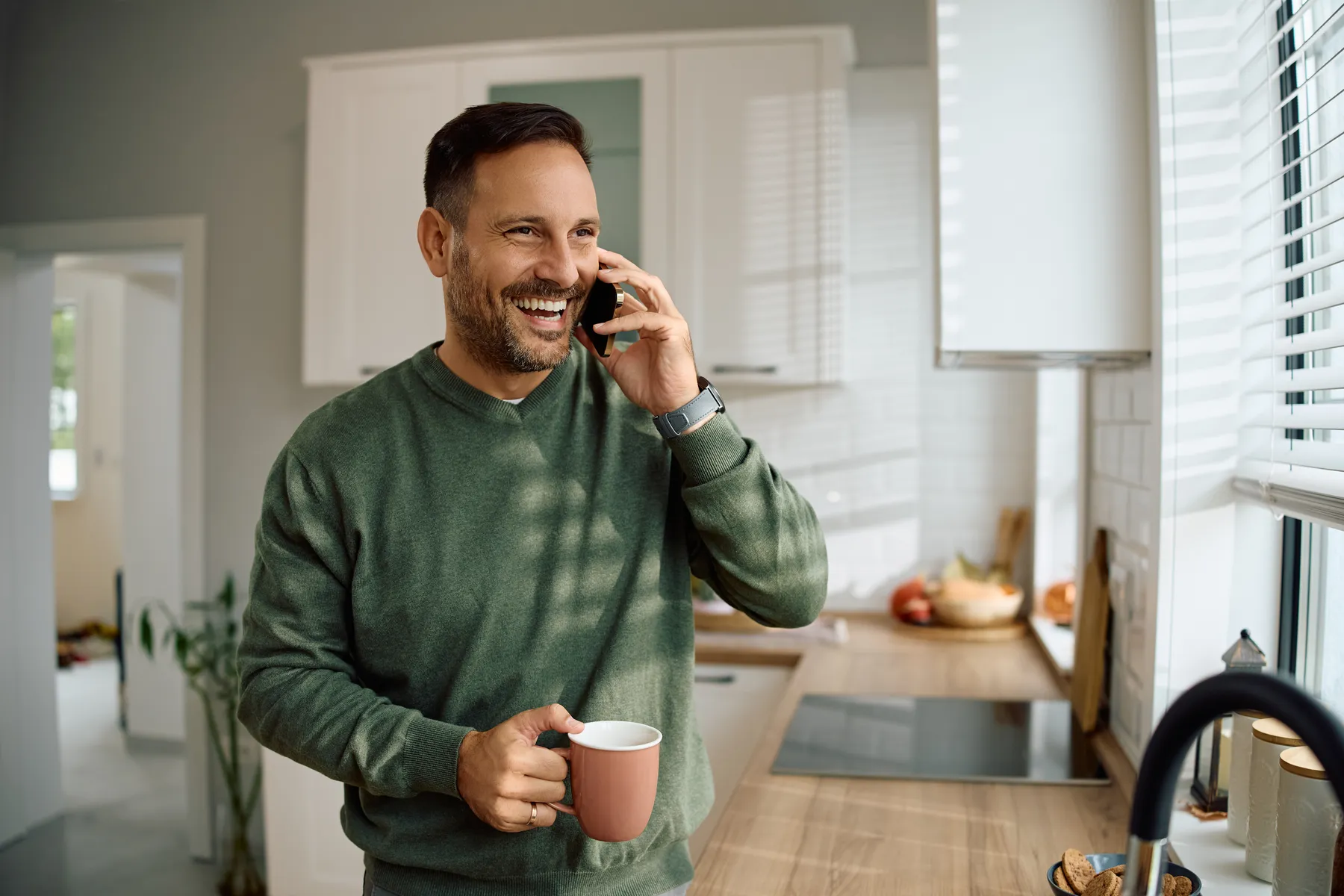 Happy client on the phone in his clean kitchen